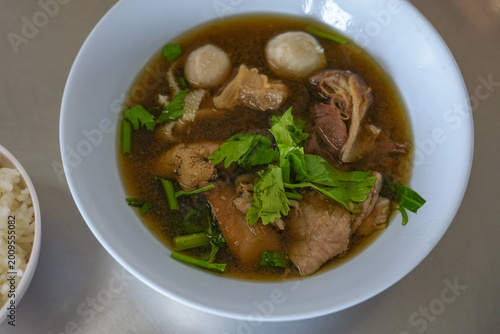 The closed up of Thai noodles. Asian noodle soup with beef meatball with fresh vegetable on wood table. 