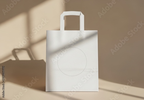 Blank white paper shopping bag with handle standing in a modern studio with soft light and shadow effects