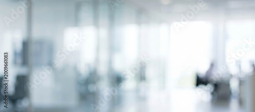 A softly blurred image of an office interior, featuring modern design elements and an open workspace. Natural light filters through large windows.