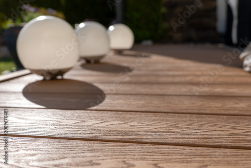 Fotografie Modern spherical lamps on WPC decking with strong shadows