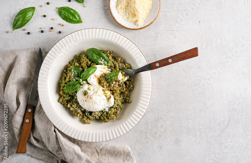 Konstfotografi Top view of Buckwheat porridge with spinach pesto and poached eggs and fork inside served on light table