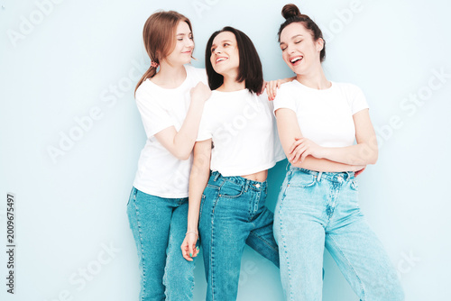 Obraz na plátně Three young beautiful smiling hipster female in trendy same summer white t-shirt and jeans clothes