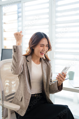 Free Download Asian business woman getting bonus reward, good news on telephone mobile phone at work in office. Happy, smiling ,winner, triumph, yes gesture. - GFXLoad