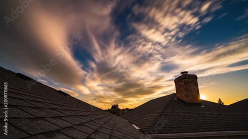 Residential rooftops under a dynamic sky with sunburst