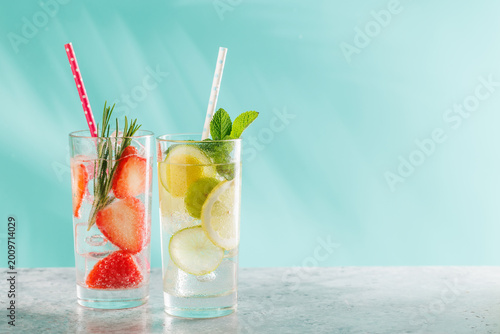 Two fresh non alcoholic drinks with strawberry and lemon on blue background
