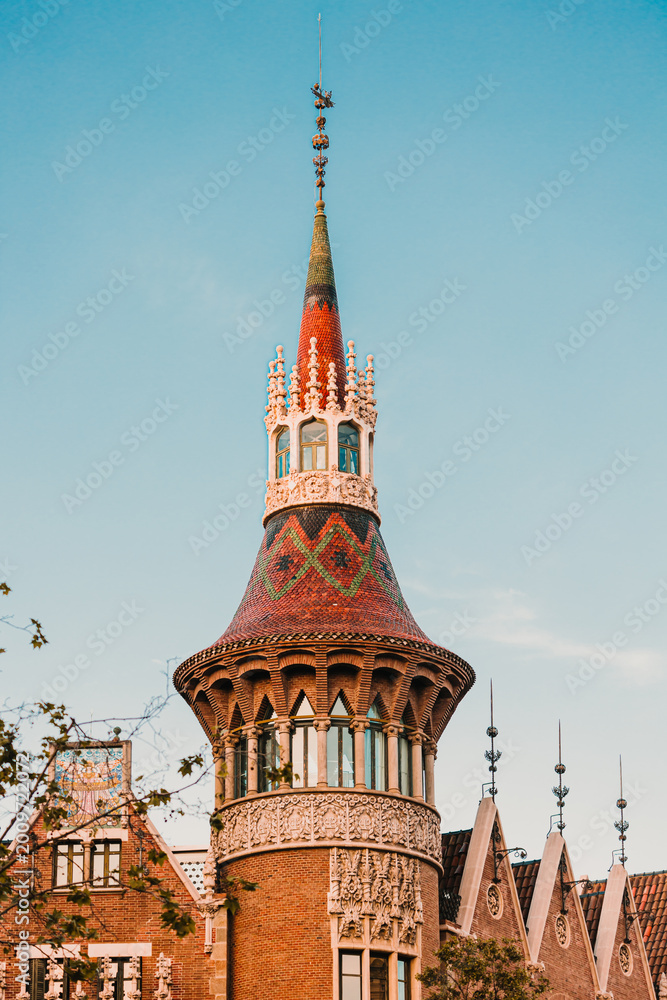 Fototapeta premium Detailed view of a decorative building spire featuring red and green tile patterns and stone carvings.