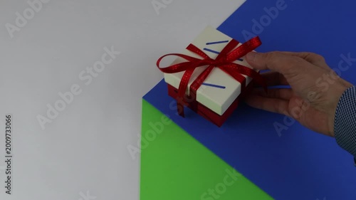 A gift package with a red bow on the tabletop, on a colorful surface with a sense of copy space and chroma key