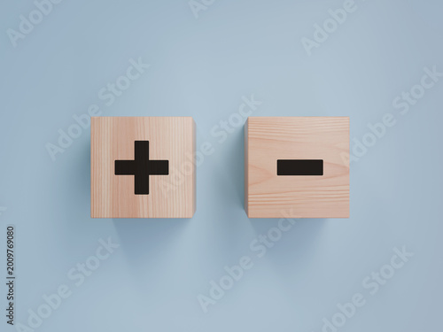 Obraz na plátně Two wooden cubes with black plus and minus symbols displayed side by side on a s