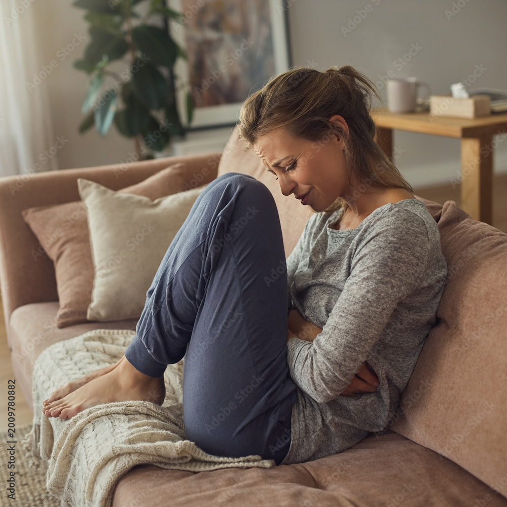 Obraz premium Woman experiencing kidney stones pain on couch with hydration therapy