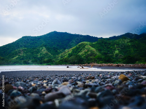 Canvas Print Serene pebble beach and tranquil stream flowing into the vast sea, framed by maj