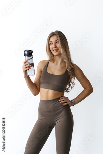 Female fitness woman holding a water bottle in a white studio environment on a white background.