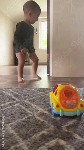 Toddler pulling toy car on string indoors