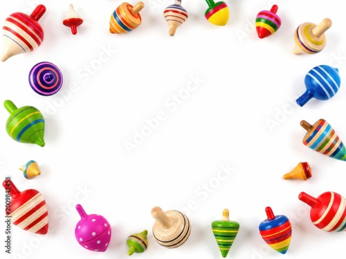 New wooden and colorful spinning tops styled as a decorative border frame with assorted painted tops in different sizes arranged around open center space isolated on pure white background