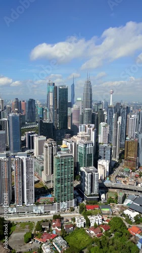 Aerial drone view of Kuala Lumpur skyline featuring modern skyscrapers, dense urban buildings and city infrastructure. Bright daytime cityscape showing rapid development in Malaysia.