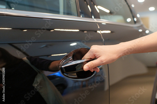 A close-up view of a hand reaching for and pulling the chrome door handle of a modern SUV car.