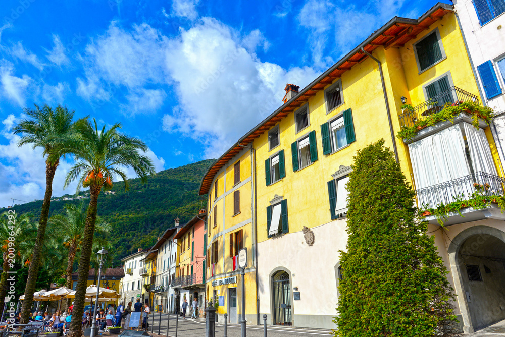Fototapeta premium Farbenfrohe Häuserzeile mit Palmen an der Promenade von Riva di Solto am Iseosee, Italien