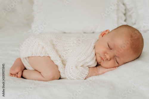 a newborn baby is sleeping, a sweet healthy baby's sleep on a white bed, space and room for text