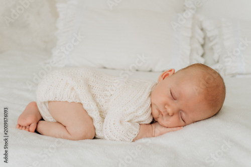 a newborn baby is sleeping, a sweet healthy baby's sleep on a white bed, space and room for text