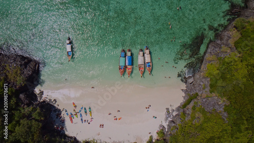 Tropical paradise beach, aerial view of vibrant turquoise ocean water, longtail boats, and kayaks on white sand. Idyllic island vacation, serene travel destination, and summer holiday escape.