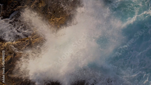Dynamic ocean waves crashing against rugged brown rocks, powerful sea spray and white foam, a dramatic natural coastal scene, perfect for environmental and travel themes.