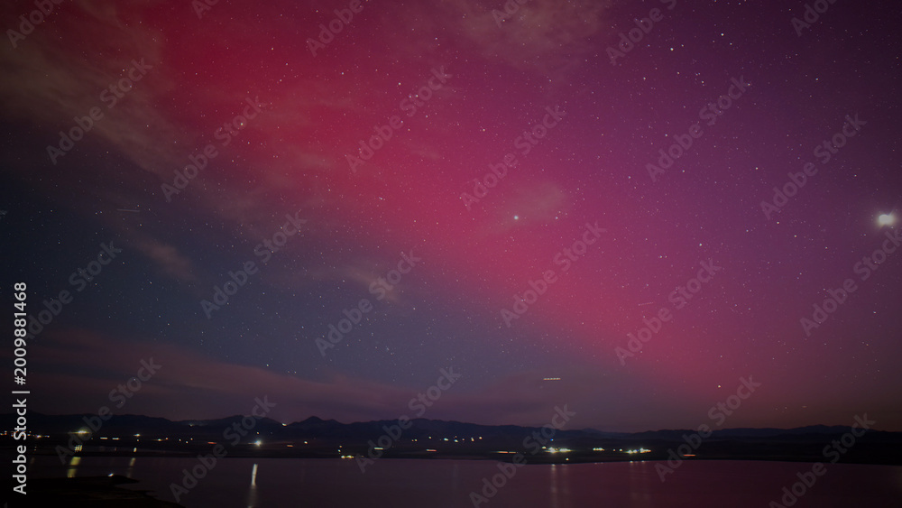 Fototapeta premium Vibrant pink and purple aurora borealis illuminating a dark night sky, stunning natural light phenomenon over a tranquil lake, celestial display for breathtaking backgrounds and atmospheric