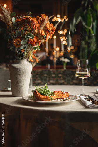 Foto Roasted pumpkin dish with greens on beautifully set restaurant table with flower