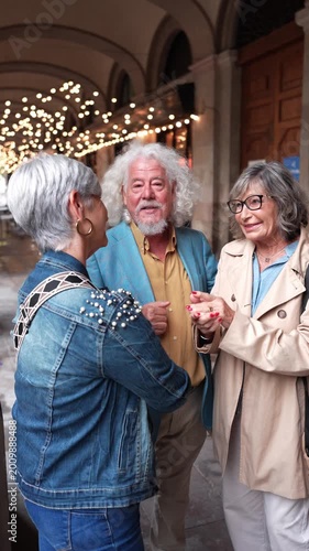 Elderly friends happily chatting and laughing together in a beautiful city arcade. Active seniors enjoying travel and their social life