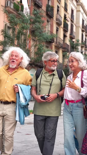 Happy senior friends walking together on a city street. Group of mature tourists exploring a european city, talking and laughing