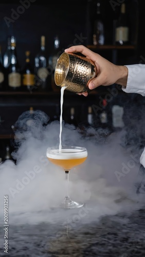 Bartender carefully pouring a cocktail with smoke effect into a glass, showcasing mixology and craft drinks in a bar setting.