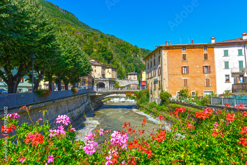 Fotografía Idyllischer Blick auf den Fluss Oglio in Edolo mit bunten Geranien im Vordergrun