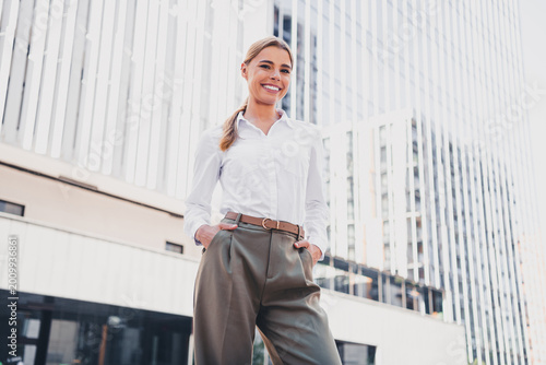 Foto Confident young business woman smiling in front of modern city office building w