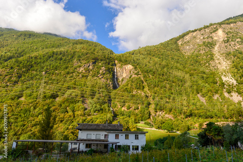 Canvas Print Idyllische Alpenlandschaft im Puschlav mit Wasserfall und ländlicher Architektur