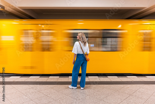 Passenger waiting for a yellow train at a Berlin subway station