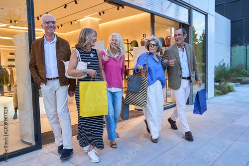 Canvas Print Senior friends enjoying shopping day carrying bags