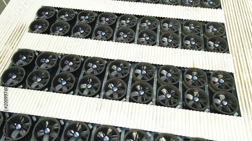 Aerial view of a massive cooling system on a data center rooftop, with countless industrial fans spinning to regulate temperature and prevent servers from overheating, ensuring data integrity