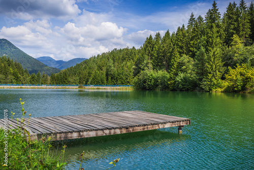 Foto Wooden pontoon pier on a natural lake with mountains in background