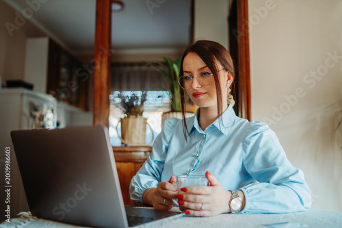 Tableau sur toile Young woman working remotely on laptop from home office