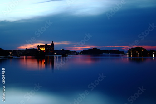 Twilight lake reflection with illuminated waterfront building and peaceful blue hour sky