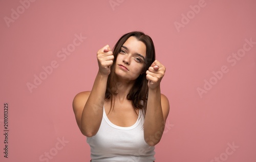 Obraz na plátně Young woman showing fig gesture, conveying defiance, scorn, and rejecting bad lu