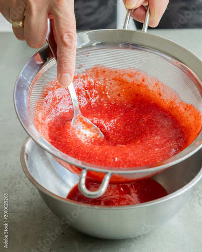 Photography Close-up of strawberry puree being strained through a fine-mesh sieve into a bow
