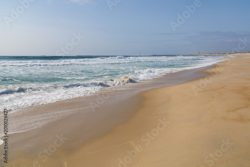 A wide sandy beach on the ocean shore on a sunny day. Scenic coastal landscape, perfect for travel, vacation, and nature backgrounds