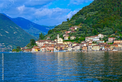 Blick vom Wasser auf das malerische Fischerdorf Peschiera Maraglio an den Hängen der Monte Isola im Iseosee, Italien