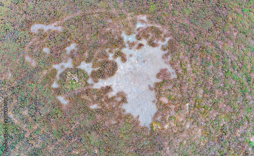 Canvas-taulu Drone capture of an irregular shallow mud pond surrounded by textured marshland