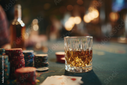 Whiskey glass and casino chips on table symbolizing gambling addiction and alcohol abuse risky lifestyle and destructive habits concept