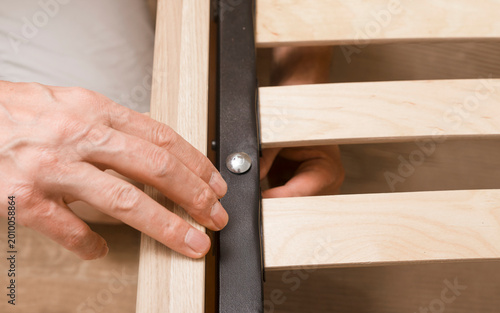 Schilderij op canvas Hand adjusting a wooden bed frame during assembly