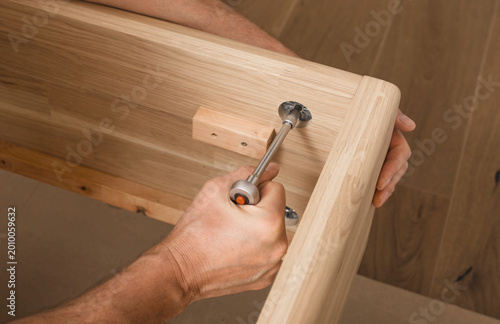 Obraz na plátně Hands tighten a screw in a wooden furniture frame