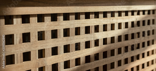 Wooden lattice panel close up. Acacia wood storage furniture with decorative grid pattern. Interior design texture for rustic decor and background..