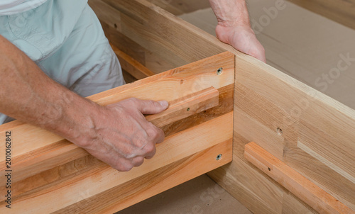 Wooden furniture assembly with hands fitting a timber joint. Close up of carpentry work in an indoor workshop. Home improvement and woodworking installation concept..