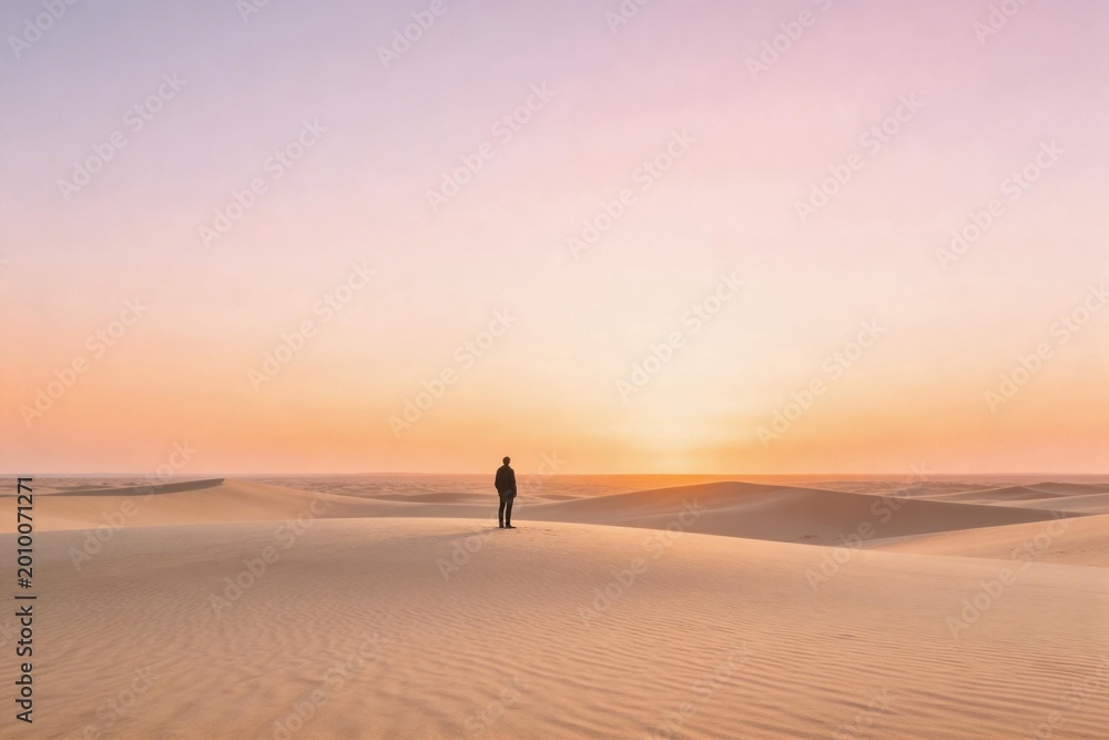 Fototapeta premium Person standing on sand dunes at sunset