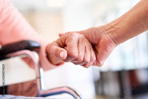 Senior Patient Hand Being Held By Physiotherapist In Rehab Center For Support And Care During Recovery Wheelchair In Background Indoors